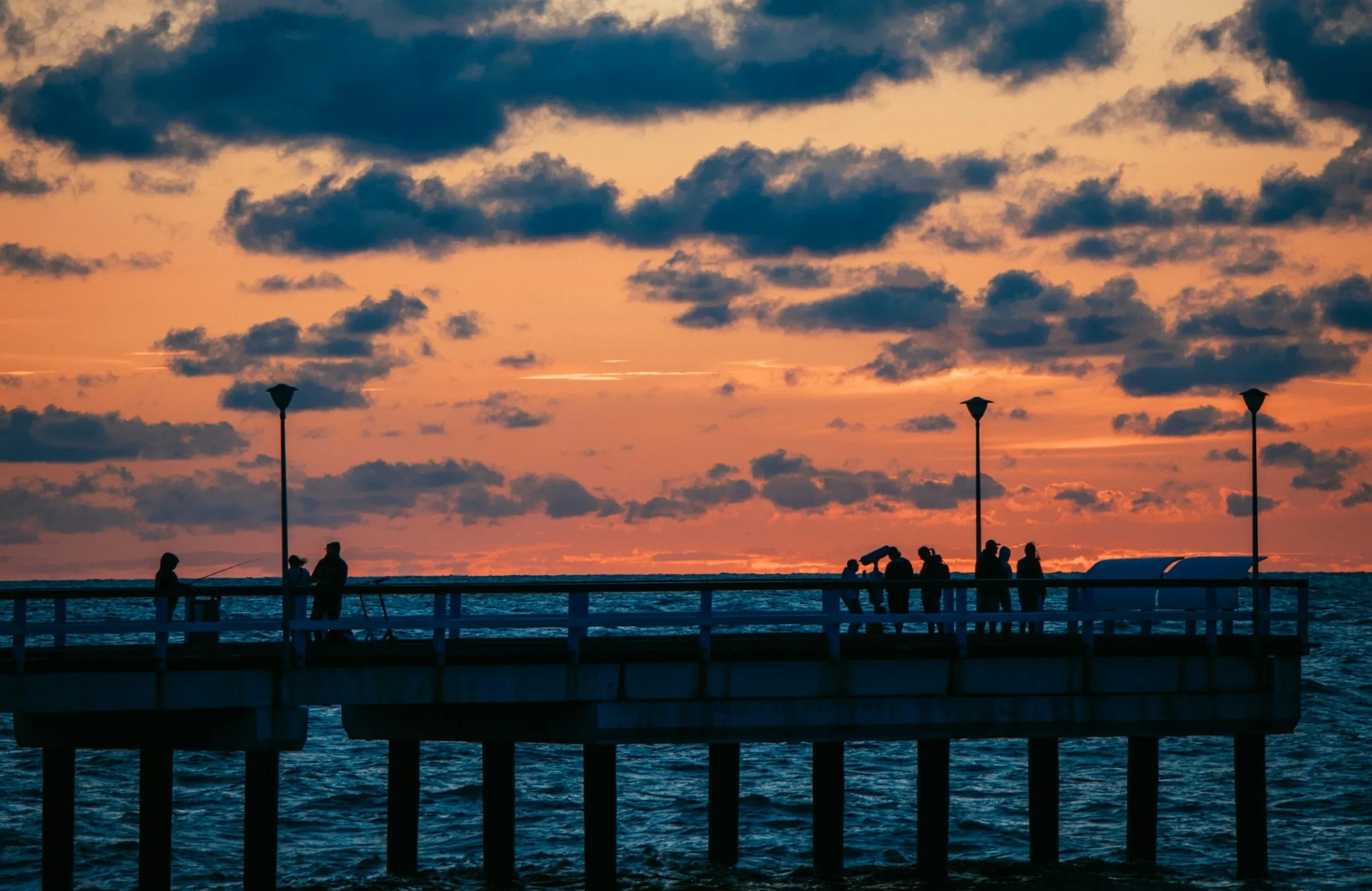 Silhouettes of people on Palanga Pier at sunset