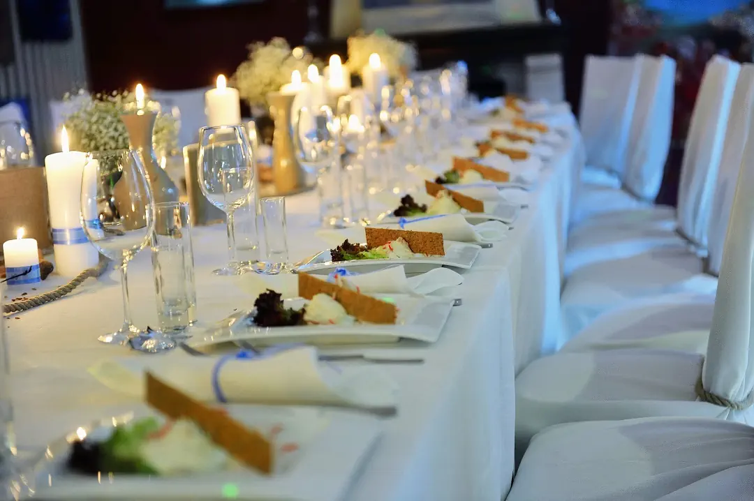 A laid banquet table at the hotel: candles, glasses and white chair covers