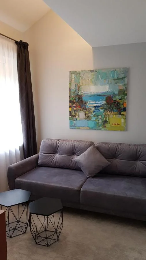 Pilka sofa su dviem staliukais po paveikslu