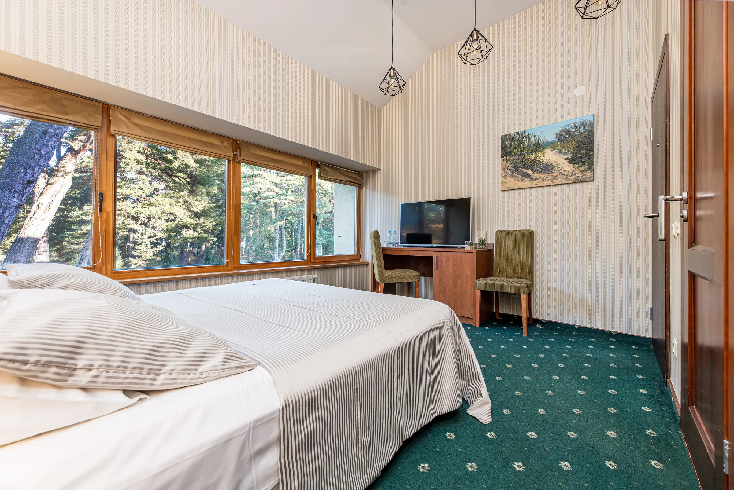 Doppelbett unter einer Dachschräge und Fenster zu den Kiefern