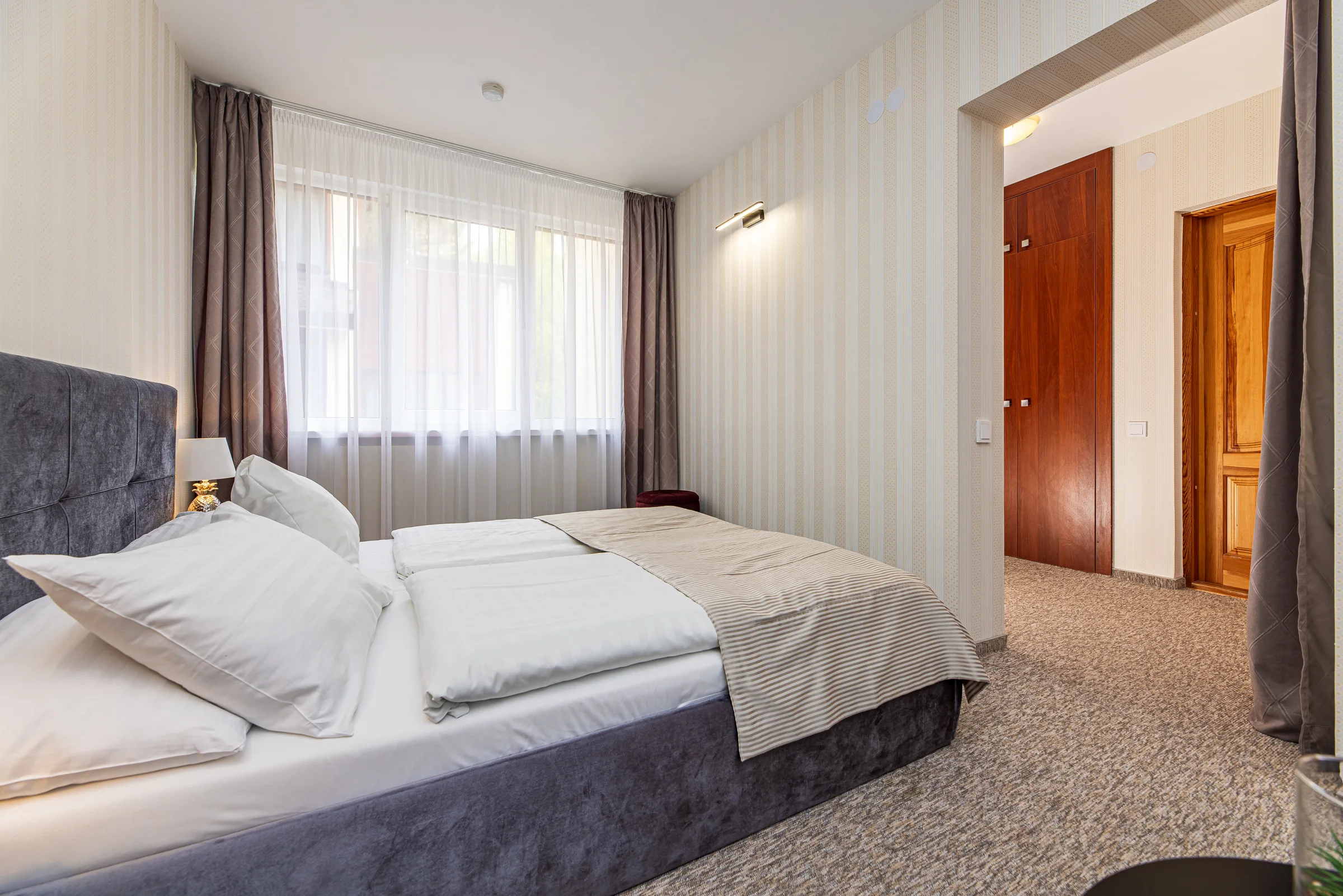 Bed and window, the open entrance door and a wooden wardrobe door