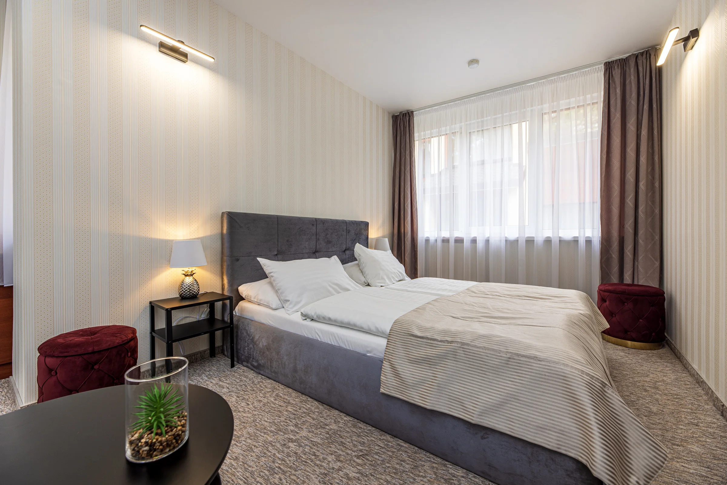 The room from the door: bed, bedside table, window and a round table