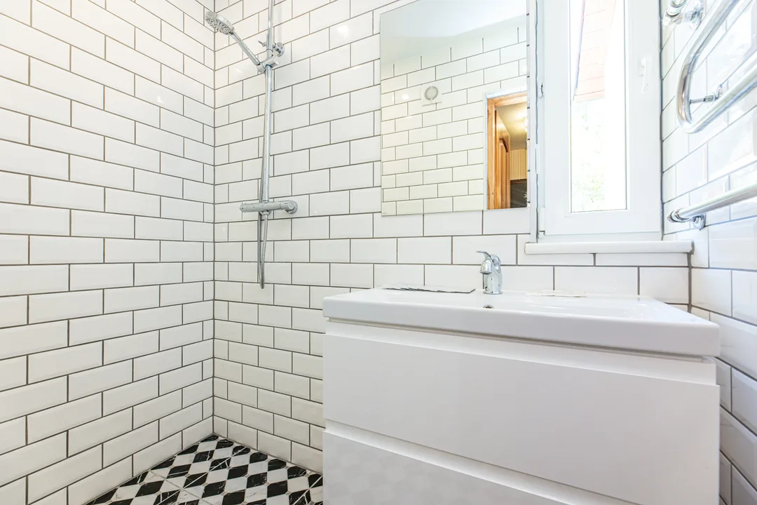Bathroom with a walk-in shower, white tiles and a white vanity