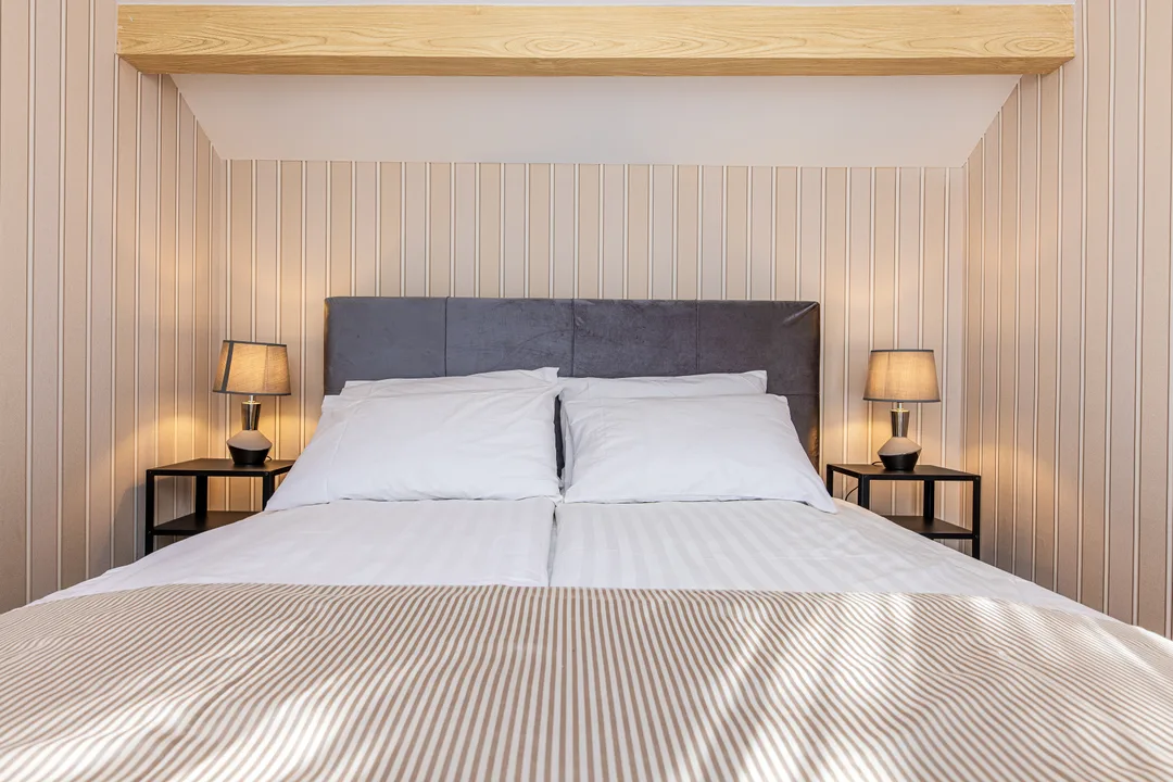 Double bed with a grey headboard and two bedside tables with lamps