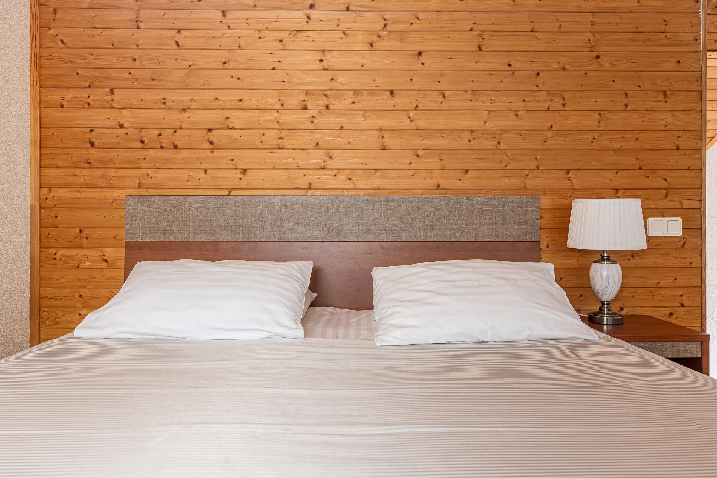 Bedroom with a padded headboard by the wooden wall