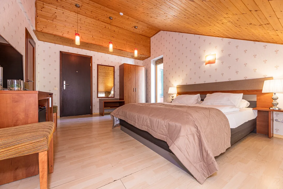The room seen from the bed towards the entrance door, wardrobe and mirror, with pendant lights
