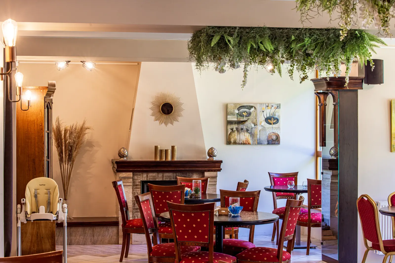 Restaurant hall with a fireplace, red chairs and paintings on the walls