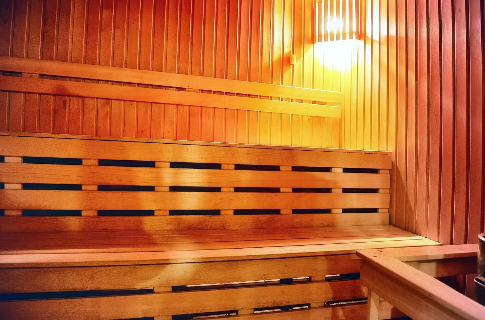 Sauna de madera con bancos y un aplique de pared